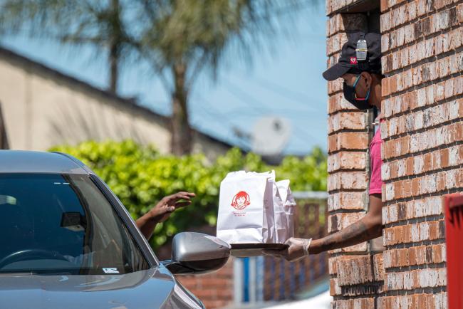 © Bloomberg. An employee wearing a protective mask and gloves hands an order to a customer at a Wendys Co. restaurant in Richmond, California, U.S., on Wednesday, May 6, 2020. Fast-food chain Wendys Co. jumped the most in a month after reporting that the sales slump caused by the Covid-19 pandemic is easing.