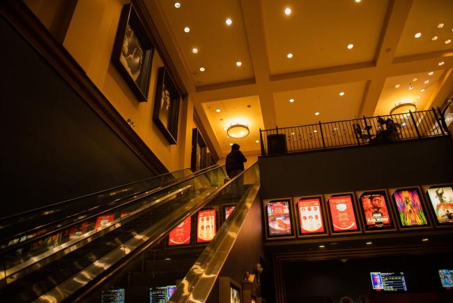 © Bloomberg. A moviegoer rides on an escalator at an AMC movie theater in New York, U.S., on Friday, March 5, 2021. The struggling U.S. box office is expected to rebound this weekend, when theaters in New York City, the second-largest U.S. movie market, reopen after a yearlong hiatus.