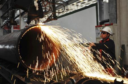 © Reuters/China Daily. A worker operates a machine to cut a pipeline at a factory in Qingdao in Shandong province on Nov. 29, 2013.