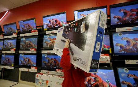 © REUTERS/Jim Young. A worker carries a television for a customer who made a purchase during Black Friday Shopping at a Target store in Chicago, Nov. 27, 2015.