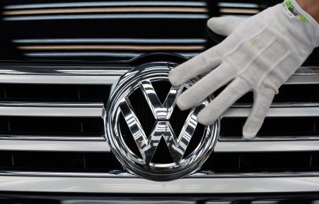 © Getty Images/Ralf Hirschberger/AFP. A picture taken on Oct. 23, 2015, shows an employee of German carmaker Volkswagen (VW) touching the VW logo on a Phaeton car at the company's Glaeserne Manufaktur (Transparent Factory) in Dresden, eastern Germany.