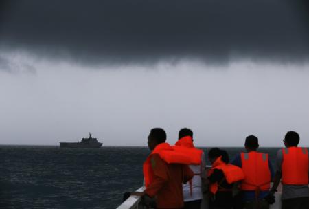 © Reuters/Beawiharta. Rescue team members look out toward the ship KRI Banda Aceh as dark clouds fill the sky during a search operation for passengers onboard AirAsia Flight 8501 in the Java Sea Jan. 4, 2015
