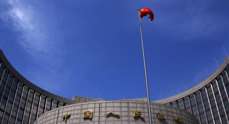 © Reuters/Petar Kujundzic. A Chinese national flag flutters in front of the headquarters of the People's Bank of China, China's central bank, in central Beijing, May 16, 2014.