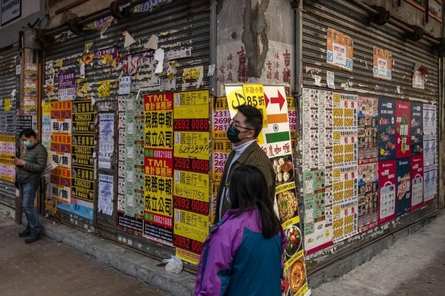 © Bloomberg. Pedestrians wearing protective masks walk past advertisements posted on a shuttered store in Hong Kong, China, on Sunday, Jan. 24, 2021. Hong Kong is scheduled to release gross domestic product (GDP) figures on Jan. 29. Photographer: Billy H.C. Kwok/Bloomberg