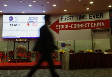 © Reuters/Bobby Yip. A man walks past a panel displaying the closing blue chip Hang Seng Index and a banner on 'Shanghai-Hong Kong Stock Connect' inside the Hong Kong Exchange in Hong Kong on March 5, 2015.