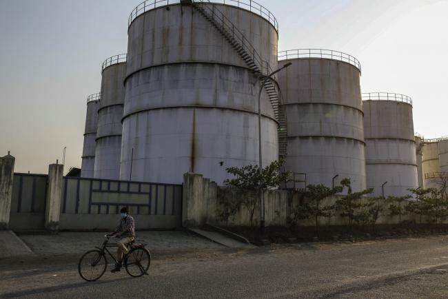 © Bloomberg. A cyclist rides past oil storage tanks in Navi Mumbai, Maharashtra, India. Photographer: Dhiraj Singh/Bloomberg