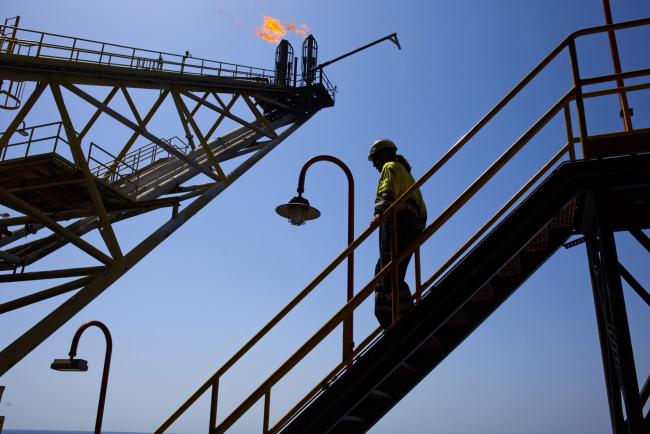 © Bloomberg. An oil worker passes the waste gas venting pipes on an oil platform off the coast of Spain. Photographer: Bloomberg Creative Photos/Bloomberg