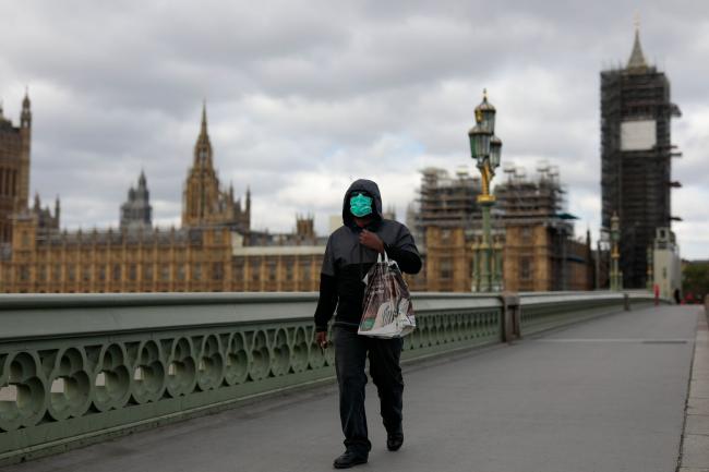 © Bloomberg. A commuter wearing a protective face mask crosses Westminster Bridge in view of the Houses of Parliament and Elizabeth Tower, also known as Big Ben, in London, U.K., on Monday, May 11, 2020. U.K. Prime Minister Boris Johnson will flesh out his plan for lifting the U.K. lockdown in Parliament as he seeks to get more people back to work, even as resistance from politicians and labor unions laid bare the hurdles facing the government as it tries to kickstart the economy. Photographer: Jason Alden/Bloomberg