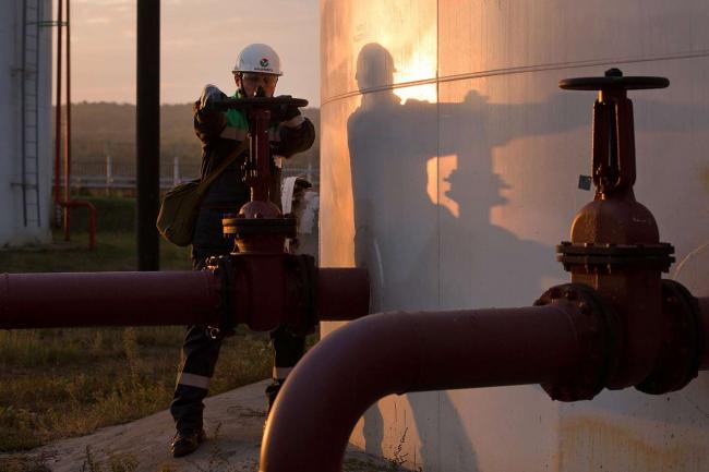 © Bloomberg. An employee turns a control valve on pipework beside a storage tank at an oil delivery point operated by Bashneft PAO in Sergeevka village, near Ufa, Russia, on Monday, Sept. 26, 2016. Bashneft distributes petroleum products and petrochemicals around the world and in Russia via filling stations. Photographer: Andrey Rudakov/Bloomberg
