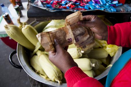 © REUTERS/Rogan Ward. South Africa's commodity-linked currency was 0.27 percent weaker at 13.3515 to the U.S. dollar compared with Friday's New York close of 13.350. Pictured: A street trader counted out change for a customer in Durban, South Africa, Sept. 8, 2015.