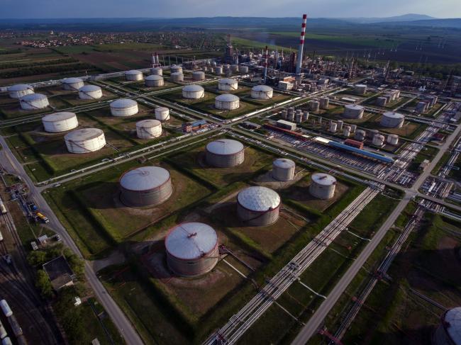 © Bloomberg. Oil storage silos stand at the oil and gas refinery operated by Naftna Industrija Srbije AD (NIS), a unit of Gazprom Neft PJSC, in this aerial photograph in Pancevo, Serbia, on Tuesday, April 28, 2020. Crude whipsawed near $11 a barrel after a major index tracked by billions of dollars in funds bailed out of near-term contracts for fear prices may turn negative again. Photographer: Oliver Bunic/Bloomberg