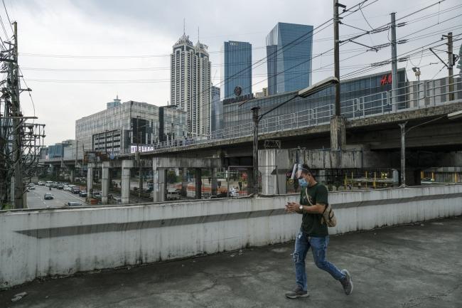 © Bloomberg. A commuter wearing a protective mask and face shield walks along an elevated walkway above the EDSA highway near the Ortigas Business district of Metro Manila, the Philippines, on Monday, Nov. 16, 2020. Typhoon Vamco barreled through Luzon from Wednesday, triggering some of Metro Manila’s worst floods in years. Photographer: Veejay Villafranca/Bloomberg