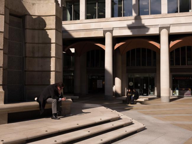 © Bloomberg. A member of the public sits outside the London Stock Exchange (LSE) in London, U.K., on Monday, March 23, 2020. The U.K. stepped in to shore up the country's rail operators after Prime Minister Boris Johnson warned Britons they face 