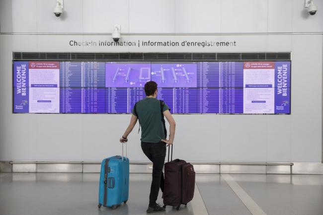 © Bloomberg. A traveler checks flight information on screens at Toronto Pearson International Airport (YYZ) in Toronto, Ontario, Canada, on Monday, March 16, 2020. Air Canada fell as much as 38%, its biggest one-day drop since going public, after Prime Minister Justin Trudeau said the country would close its borders to all foreign travelers except Americans. Photographer: Cole Burston/Bloomberg