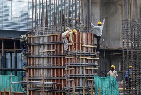 © Reuters/Shailesh Andrade. Labourers work at the site of a commercial building under construction in Mumbai, Nov. 28, 2014.