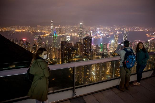 © Bloomberg. People look at the city's skyline from a viewing terrace at Victoria Peak in Hong Kong, China, on Monday, Feb. 3, 2020. The outlook for the Hong Kong economy in 2020 is “subject to high uncertainties” including the global economic recovery, U.S.-China trade relations, the ongoing protests and the progression of the viral outbreak, the government said in a release. Photographer: Paul Yeung/Bloomberg
