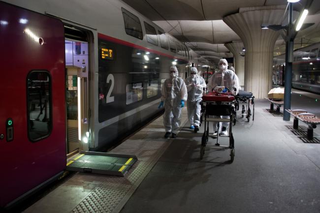 © Bloomberg. Medical personnel wheel a gurney along a railway platform in Paris on April 5. Photographer: Nathan Laine/Bloomberg
