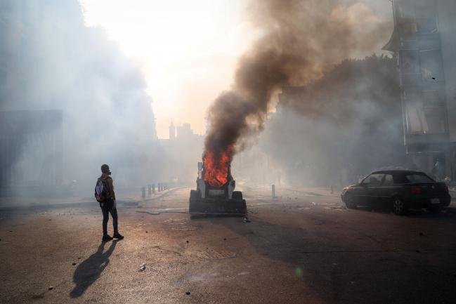© Bloomberg. A protester stands alongside an excavator on fire during a demonstration close to parliament in Beirut, Lebanon, on Saturday, Aug. 8, 2020. Lebanese protesters took to the streets of Beirut on Saturday amid growing anger at the government following the devastating blast that killed dozens this week.