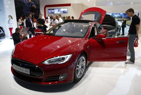 © Reuters/Benoit Tessier. Visitors look at a Tesla Model S car on display on Media Day at the Paris Mondial de l'Automobile, Oct. 2, 2014.