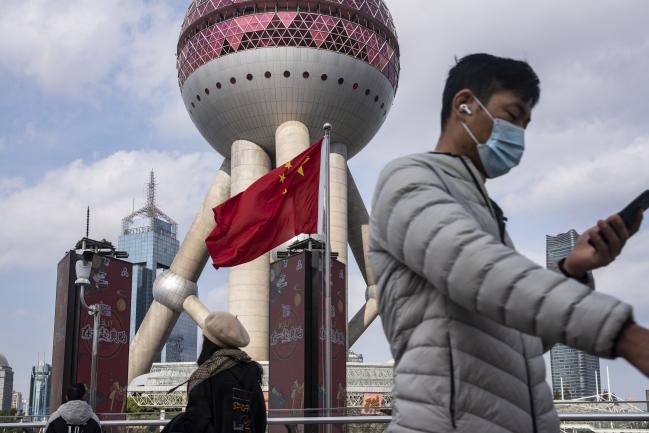 © Bloomberg. Pedestrians walk past a Chinese flag in the Lujiazui financial district in Shanghai, China, on Tuesday, Dec. 1, 2020. China unexpectedly added medium-term funding to the financial system on Monday, as the central bank sought to ease liquidity tightness in the final weeks of the year. Photographer: Qilai Shen/Bloomberg