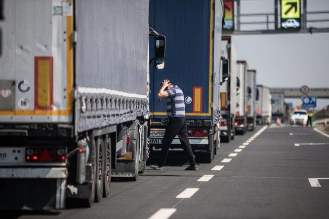 © Bloomberg. Haulage trucks stand in a queue of heavy traffic whilst waiting to cross the border into Romania in Nagylak, Hungary, on Wednesday, April 8, 2020. Across the globe, truckers are encountering delays along distribution chains snarled by the coronavirus pandemic. Photographer: Akos Stiller/Bloomberg