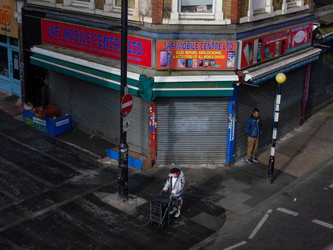 © Bloomberg. Pedestrians walk past a shuttered store in the Brixton district of London on April 4. Photographer: Simon Dawson/Bloomberg
