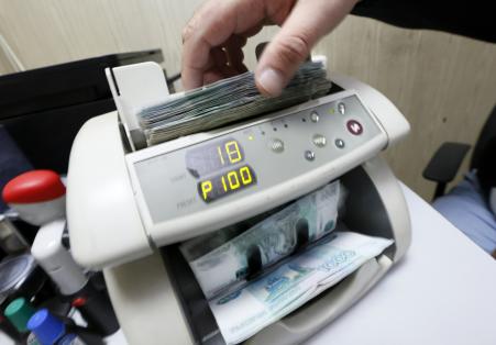 © Reuters/Ilya Naymushin. An employee uses a machine while counting Russian ruble banknotes at a private company's office in Krasnoyarsk, Siberia, December 17, 2014.