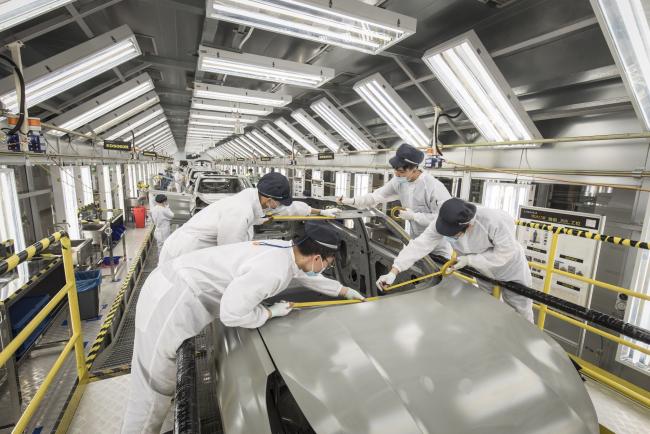 © Bloomberg. Employees wearing protective masks place yellow tape on a Lynk & Co. 05 crossover sport utility vehicle (SUV) in the paint shop at the Geely Automobile Holdings Ltd. plant in Ningbo, Zhejiang Province, China, on Tuesday, April 28, 2020. China's manufacturing purchasing managers' index (PMI) jumped to 52 in March, from an historic low of 35.7 in February as activity rebounded from disruptions caused by the coronavirus and containment measures. Photographer: Qilai Shen/Bloomberg