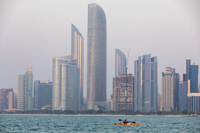 © Bloomberg. An Emirati woman paddles a canoe past skyscrapers in Abu Dhabi, United Arab Emirates, on Wednesday, Oct. 2, 2019. Abu Dhabi sold $10 billion of bonds in a three-part deal in its first international offering in two years as it takes advantage of relatively low borrowing costs.