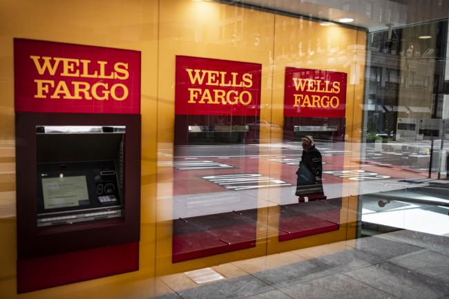 © Bloomberg. A person wearing a protective mask is reflected in the window of a temporarily closed Wells Fargo & Co. Bank branch in New York on April 10. Photographer: Mark Kauzlarich/Bloomberg