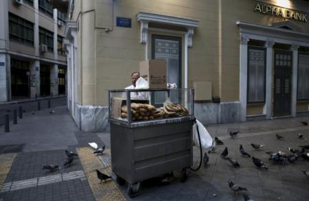 © Reuters/Alkis Konstantinidis. A man sells bread rolls outside an Alpha Bank branch in Athens, Greece on June 26, 2015.