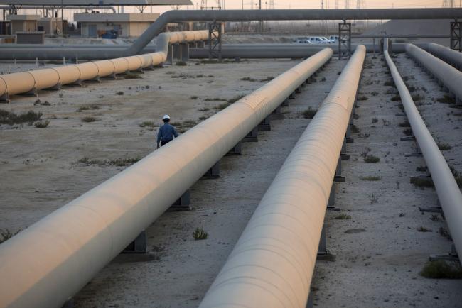 © Bloomberg. An employee walks along transport pipes leading to oil storage tanks at the Juaymah tank farm at Saudi Aramco's Ras Tanura oil refinery and oil terminal in Ras Tanura, Saudi Arabia, on Monday, Oct. 1, 2018.  Photographer: Simon Dawson/Bloomberg