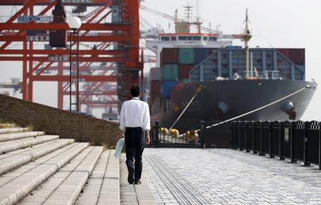 © Reuters/Toru Hanai. The Bank of Japan (BoJ) kept its monetary policy unchanged Thursday even as the country's exports -- hit by a weakening demand in China -- fell for the first time in over a year. Pictured: A man walks near a container ship at a port in Tokyo, Japan, Oct. 20, 2015.