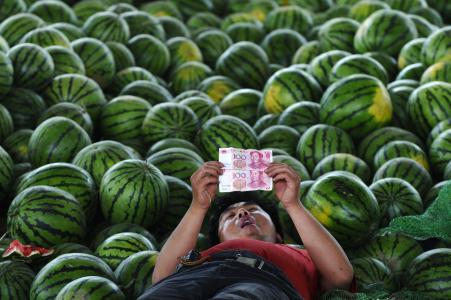 © Reuters. A watermelon vendor looks at yuan banknotes at a market in Changzhi, Shanxi province on June 21, 2010.