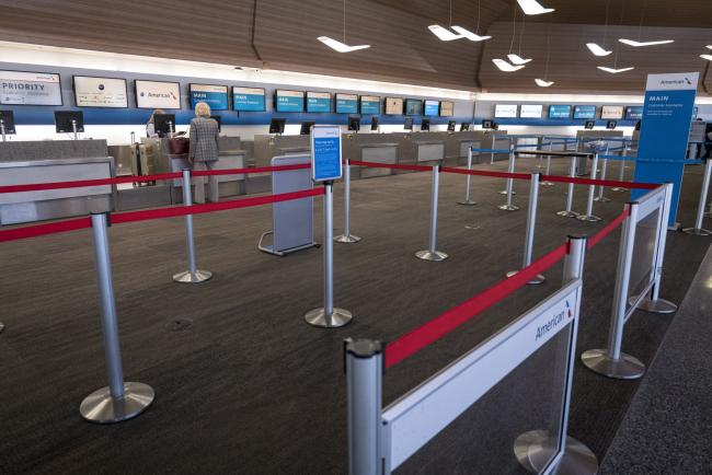 © Bloomberg. A traveler checks in at an otherwise empty American Airlines counter inside San Francisco International Airport on April 2. Photographer: David Paul Morris/Bloomberg