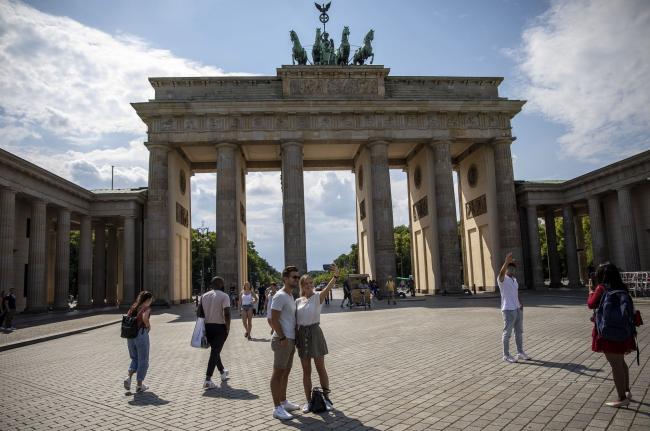 © Bloomberg. BERLIN, GERMANY - JUNE 19: Tourists stand at Brandenburg Gate during the novel coronavirus pandemic on June 19, 2020 in Berlin, Germany. Travel restrictions originally imposed to stem the spread of the virus have mostly been lifted across the European Union and businesses dependent on tourism are anxiously waiting for tourists to return in large numbers. (Photo by Maja Hitij/Getty Images)