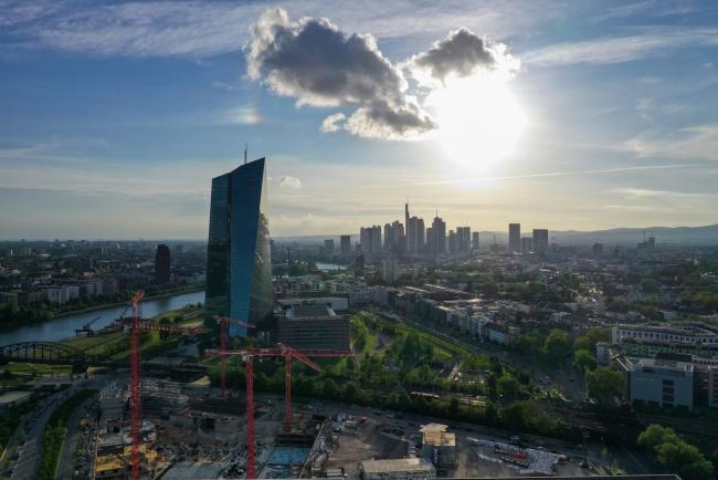 © Bloomberg. The European Central Bank (ECB) headquarters, left, stands near skyscrapers on the financial district skyline in this aerial photograph in Frankfurt, Germany, on Tuesday, April 28, 2020. The ECB’s response to the coronavirus has calmed markets while setting it on a path that could test its commitment to the mission to keep prices stable.