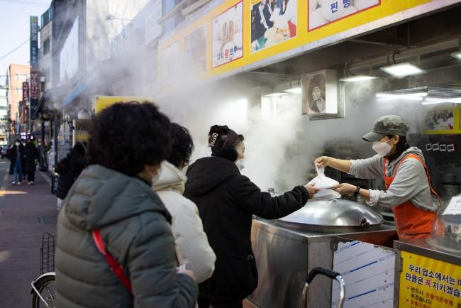 © Bloomberg. A customer wearing a protective face mask pays for her purchase at a dumpling store in Mangwon Market in Seoul, South Korea, on Tuesday, Feb. 9, 2021. South Korea relaxed its social distancing rules on Monday, allowing longer opening hours for some retail businesses, as the number of new coronavirus infections declines. Photographer: SeongJoon Cho/Bloomberg