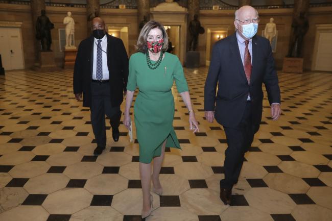 © Bloomberg. U.S. House Speaker Nancy Pelosi, a Democrat from California, center, and Senator Patrick Leahy, a Democrat from Vermont, right, walk to the House Chamber at the U.S. Capitol in Washington, D.C., U.S., on Monday, Dec. 21, 2020. The House was poised to vote Monday on a massive 5,593-page package of legislation that combines pandemic relief with a bill to fund government operations just hours after lawmakers got the text.