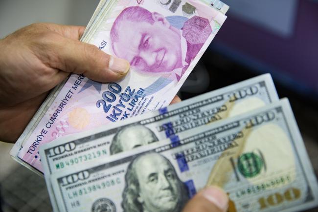 © Bloomberg. A customer holds Turkish two-hundred Lira banknotes, left, and U.S. one-hundred dollar banknotes, inside a foreign currency exchange bureau in the Beyoglu district of Istanbul, Turkey on Wednesday, Oct. 9, 2019. The lira hovered near its lowest level since late August against the dollar while stocks and government bonds fell as the threat of U.S. penalties mounted after a Turkish military operation in northeast Syria got underway. Photographer: Kerem Uzel/Bloomberg