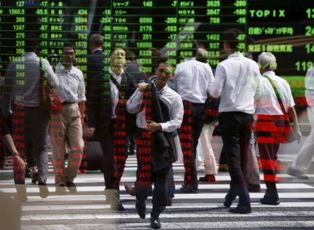 © Reuters. Passers-by are reflected on a stock quotation board at a brokerage in Tokyo, Sept. 29, 2015.