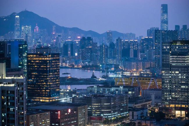 © Bloomberg. A construction site in the Kai Tak area, center, stands among illuminated buildings at dusk in Hong Kong, China, on Thursday, Feb. 20, 2020. Apartment rents in Hong Kong have dropped to the lowest in almost two years as people leave the city and home owners try to lease rather than sell. Photographer: Billy H.C. Kwok/Bloomberg