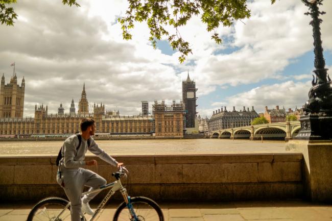 © Bloomberg. A cyclist travels along the Thames Path in view of the Houses of Parliament in London on May 11. Photographer: Jason Alden/Bloomberg