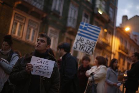 © Reuters/Rafael Marchante. A man holds a placard during a vigil to support the newly elected Greek government, outside the European Commission headquarters in Lisbon on Feb. 11, 2015.