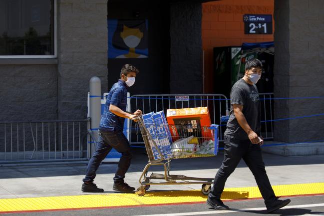 © Bloomberg. Shoppers wearing protective masks leave a Walmart store in Lakewood, California, U.S., on Thursday, July 16, 2020. Walmart Inc. will require customers to wear masks in all of its U.S. stores to protect against the coronavirus, an admission that the nation's pandemic has reached new heights and setting up potential confrontations with customers who refuse to don them. Photographer: Patrick T. Fallon/Bloomberg