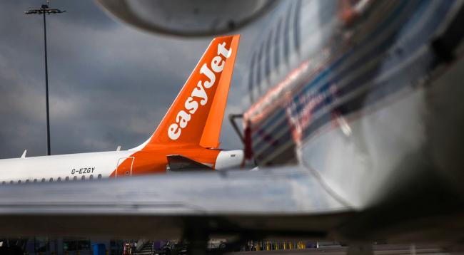 © Bloomberg. The livery of EasyJet Plc sits on the tail-fin of a passenger aircraft on the tarmac at London Luton Airport in Luton, U.K., on Friday, May 1, 2020. Ryanair Holdings Plc will cut 3,000 jobs and said it will challenge some 30 billion euros ($33 billion) in state aid being doled out to save its European competitors.