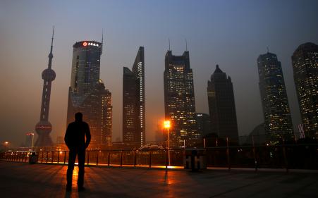 © Reuters/Carlos Barria. Chinese markets rallied after a major drop on Monday due to sustained government intervention. In this photo, a man looks at the Pudong financial district of Shanghai on Nov 20, 2013.