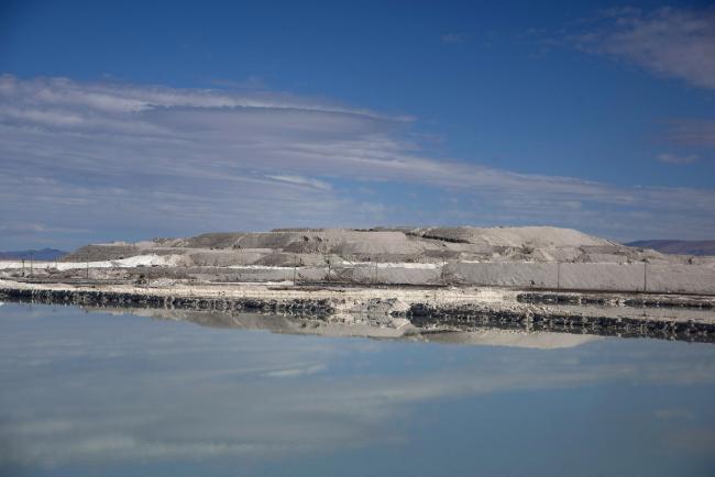 © Bloomberg. Stockpiles of lithium carbonate and salt by-product are reflected in a brine lake at a Sociedad Química y Minera de Chile (SQM) lithium mine on the Atacama salt flat in the Atacama Desert, Chile, on Wednesday, May 29, 2019. Almost three-quarters of the world’s lithium raw materials come from mines in Australia or briny lakes in Chile, giving them leverage with customers scrambling to tie-up supplies. The mining nations hope to bring refining and manufacturing plants that could help kickstart domestic technology industries.