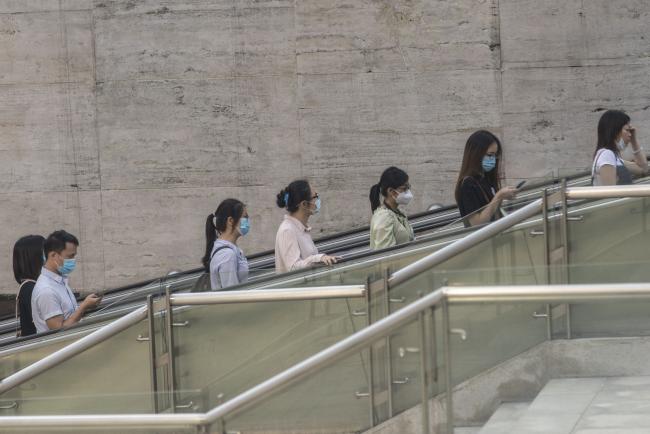 © Bloomberg. Morning commuters wearing protective masks ride on an escalator at a plaza in downtown Guangzhou, China, on Wednesday, May 13, 2020. The Pearl River Delta industrial belt has served as one of China’s most important growth engines since the Communist Party opened the economy four decades ago, propelling its rise to become one of the world’s leading powers. But now in Guangdong the situation is getting dire in some labor-intensive sectors where the widespread struggle to earn cash risks turning into a big political problem for Chinese President Xi Jinping. Photographer: Qilai Shen/Bloomberg