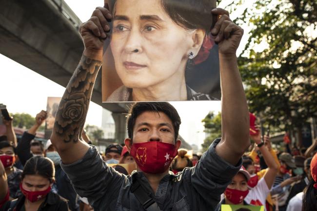 © Bloomberg. A demonstrator holds up an image of Aung San Suu Kyi during a protest outside the Embassy of Myanmar in Bangkok, Thailand, on Monday, Feb. 1 2021.  Photographer: Andre Malerba/Bloomberg